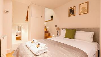 A hotel room with a bed, a nightstand, a lamp, a green pillow, and a framed picture on the wall.