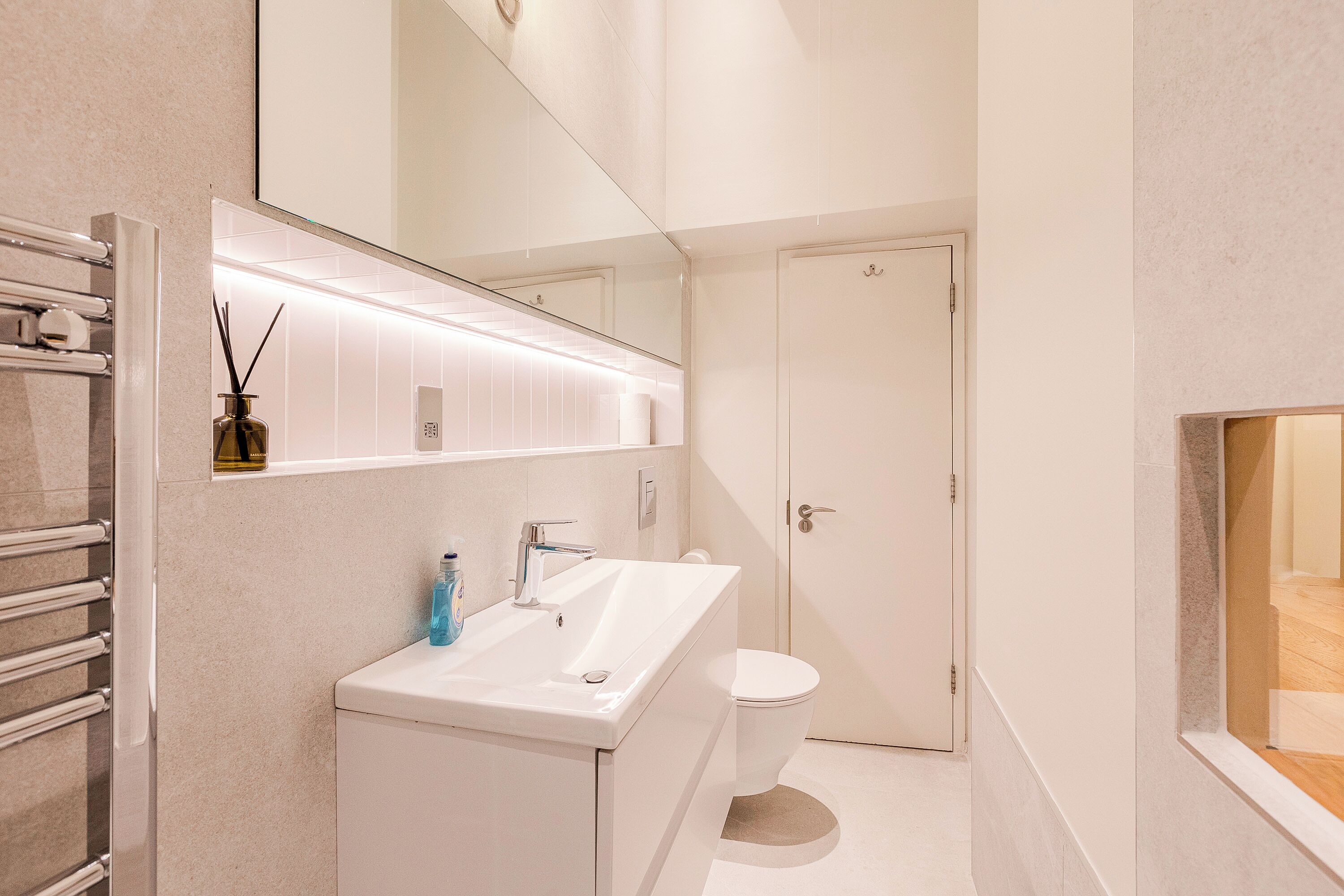 Un bagno moderno con lavandino, specchio e servizi igienici bianchi.