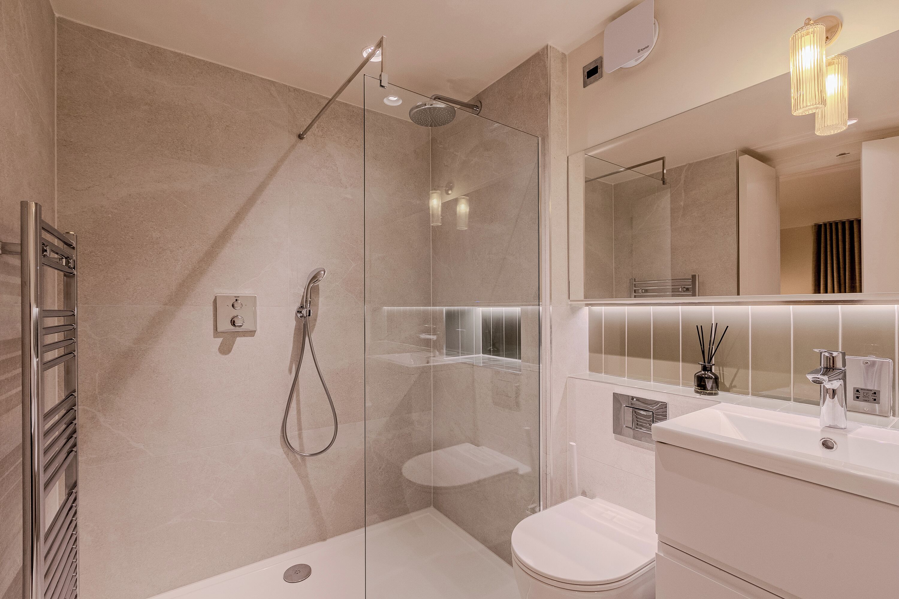 A modern bathroom with a glass-enclosed shower, a white sink, and a toilet.