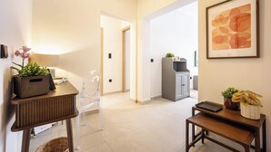 A modern living room with a wooden coffee table, a clear chair, and a small side table with a plant. - Stylish 1BR in Pangrati | Balcony & Green View (Athina)