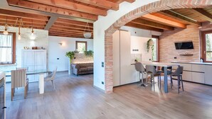 A modern kitchen with a brick wall, wooden beams, and a dining area with a table and chairs.