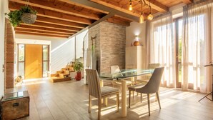 A spacious room with a glass dining table, wooden chairs, and a staircase leading to another level.