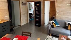 A modern living room with a grey sofa, wooden flooring, and a bookshelf filled with books. - Comfortable 44m² apartment, Eaux-Bonnes, close to ski resorts and hiking trails (Eaux-Bonnes)
