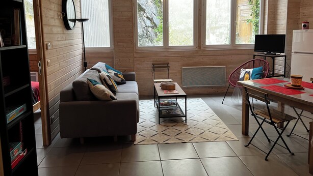 A cozy living room with a sofa, a dining table, and a TV. - Comfortable 44m² apartment, Eaux-Bonnes, close to ski resorts and hiking trails (Eaux-Bonnes)