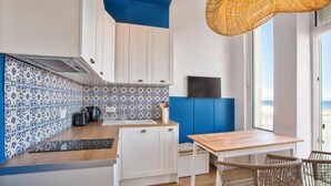 Eine moderne Küche mit weißen Schränken, einer Rückwand mit blauem Muster und einem Holztisch mit Korbstühlen.
