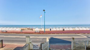 Eine Küstenpromenade mit rotem Weg, Bänken und einem Fahnenmast.