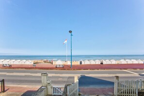 A coastal promenade with a red walkway, benches, and a flagpole. - Bleu Horizon - Studio with balcony and sea view (Villers-sur-Mer)
