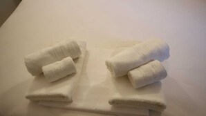 Un joc de tovalloles blanques acuradament doblegades sobre un llit.