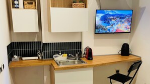 A compact kitchen with a wooden countertop, a sink, and a black folding chair. - Casa Amicitia Spanish Steps (Roma)