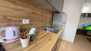 Una cocina moderna con encimera de madera, pileta de acero inoxidable y hervidor rosa.
