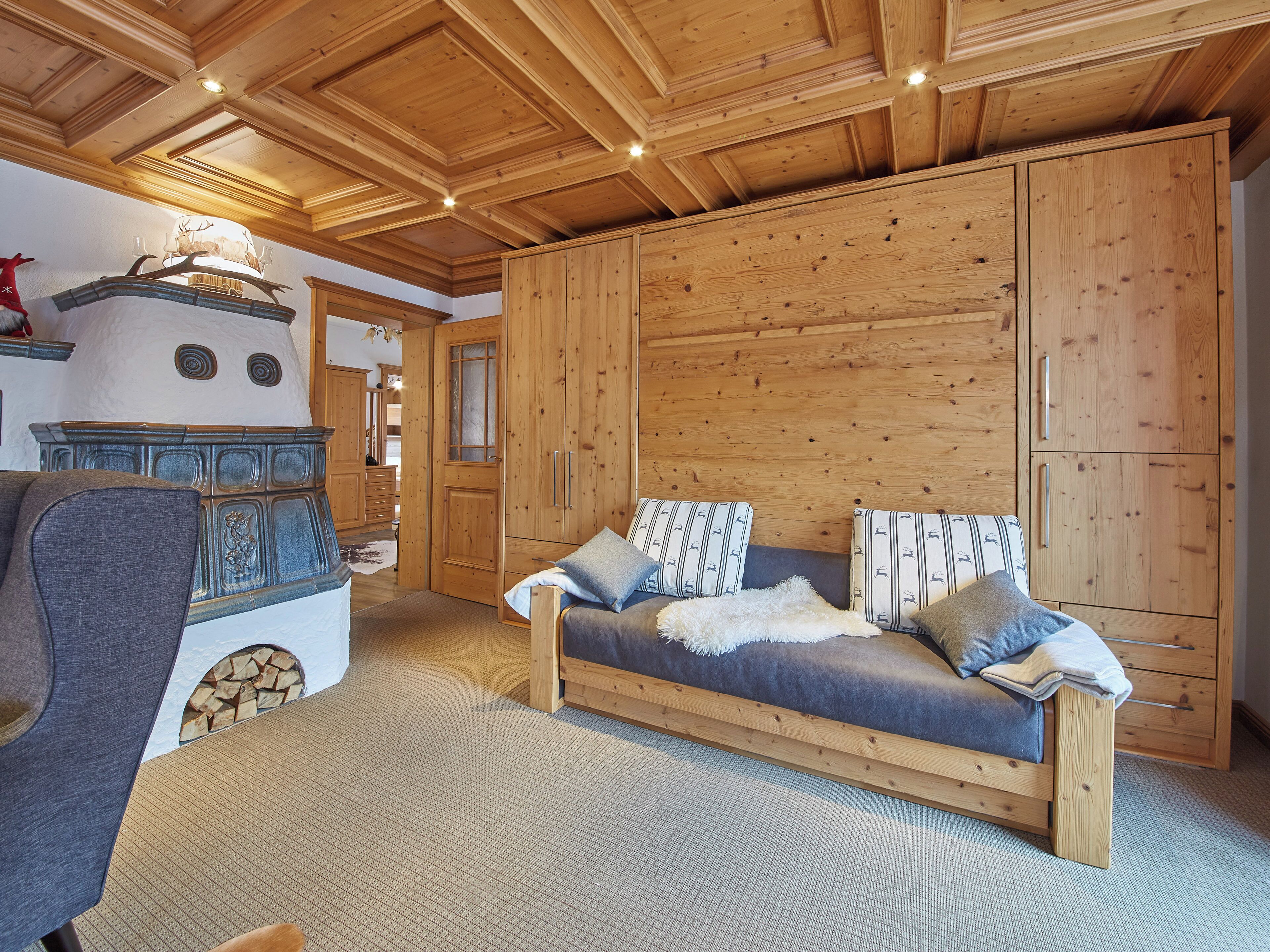 Une pièce chaleureuse avec un plafond en bois, un lit agrémenté d’oreillers à motifs et une grande armoire en bois.