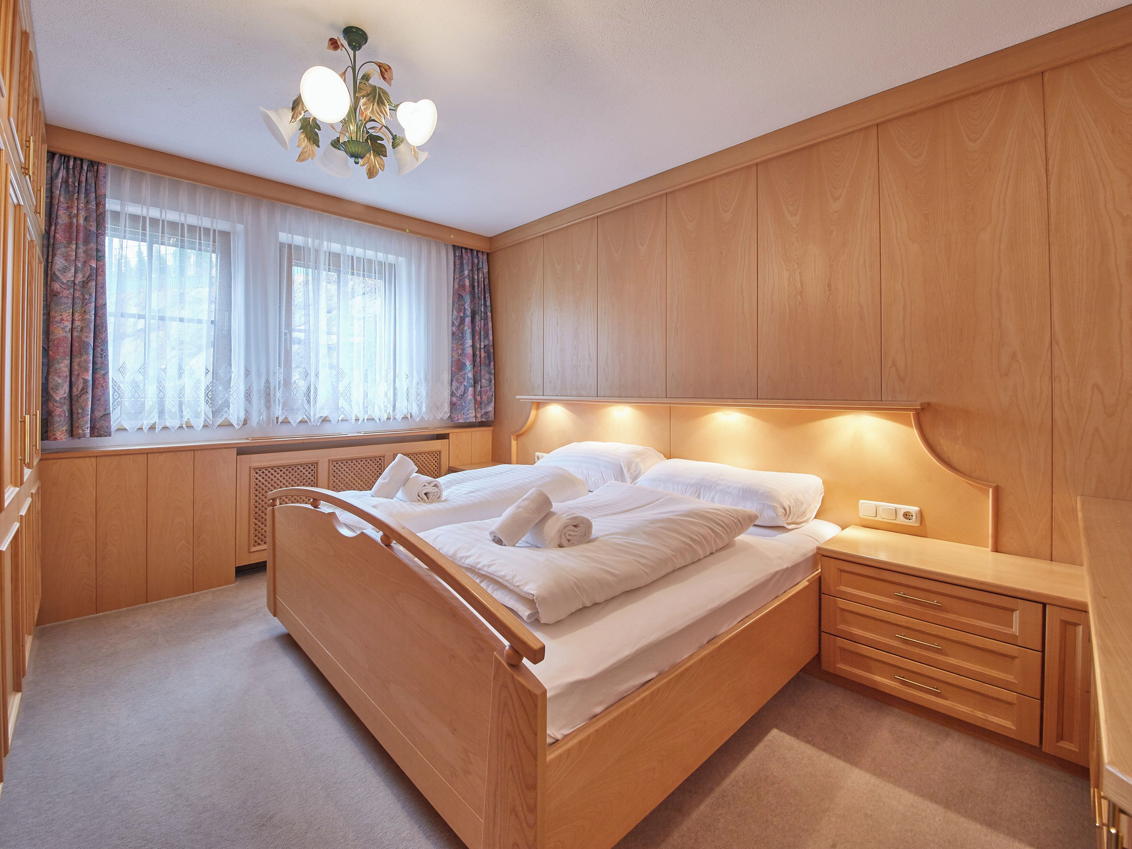 Une chambre à coucher avec un lit en bois, une table de chevet et une armoire intégrée.