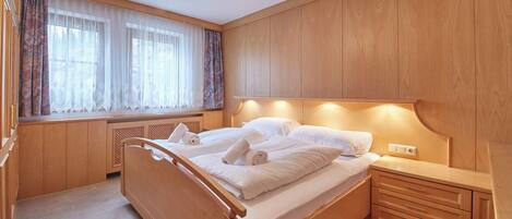 Une chambre à coucher avec un lit en bois, une table de chevet et une armoire intégrée.