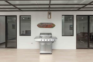 A modern kitchen with a stainless steel grill, a welcome sign, and large windows. - Casa Aurora Oasis with Private Patio & Pool (Playas Del Coco)
