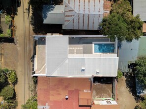 An aerial view of a residential area with a swimming pool, a red-roofed building, and a green-roofed building. - Casa Aurora with Private Patio & Pool (Playas Del Coco)