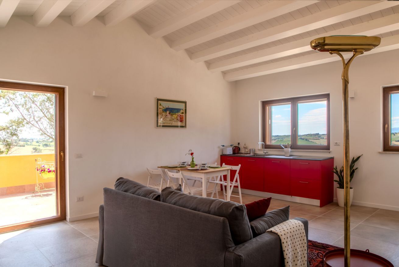Un salón espacioso con sofá, mesa de comedor y cocina con armarios rojos.