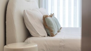 Ein modernes Badezimmer mit Toilette in Weiß, einer Badewanne in Beige und einem Fenster mit durchsichtigen Vorhängen.