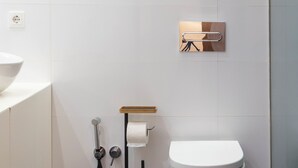 Ein modernes Badezimmer mit Toilette, Waschbecken und Duschbereich.