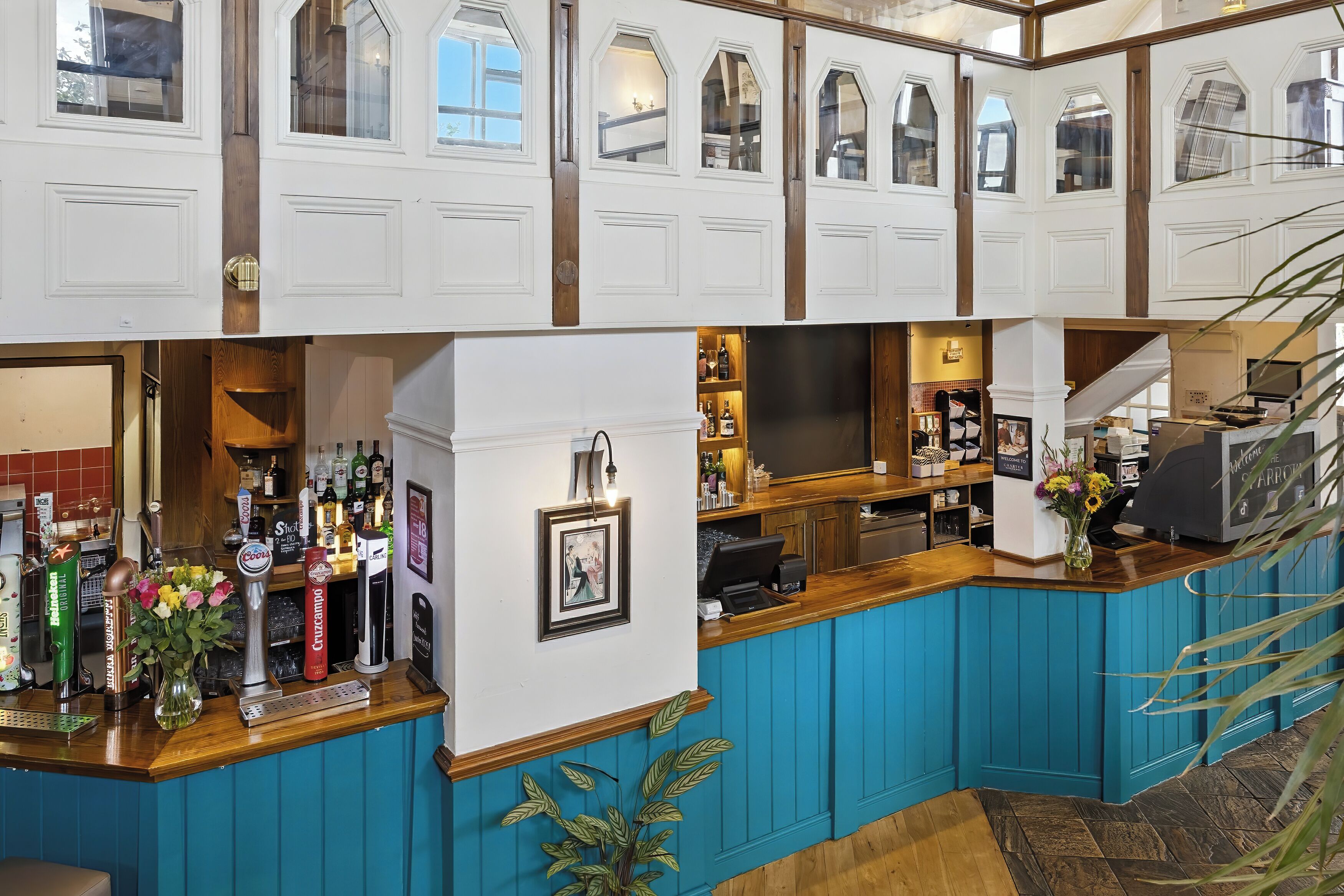 A bar area with a counter, bar stools, and a variety of bottles and glasses.