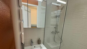 A modern bathroom with a glass shower enclosure, a white sink, and a mirror. - Cozy studio for 4 in Châtel with terrace and parking (Châtel)