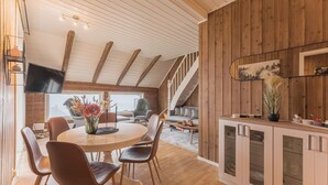 A modern kitchen with wooden accents, a dining area with a round table and chairs, and a staircase leading to an upper level. - Top-Floor Apartment – 5 Min Walk to Lillehammer’s Main Street (Innlandet)