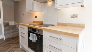 Eine moderne Küche mit weißen Schränken, einem schwarzen Backofen und einer Holz Arbeitsplatte.