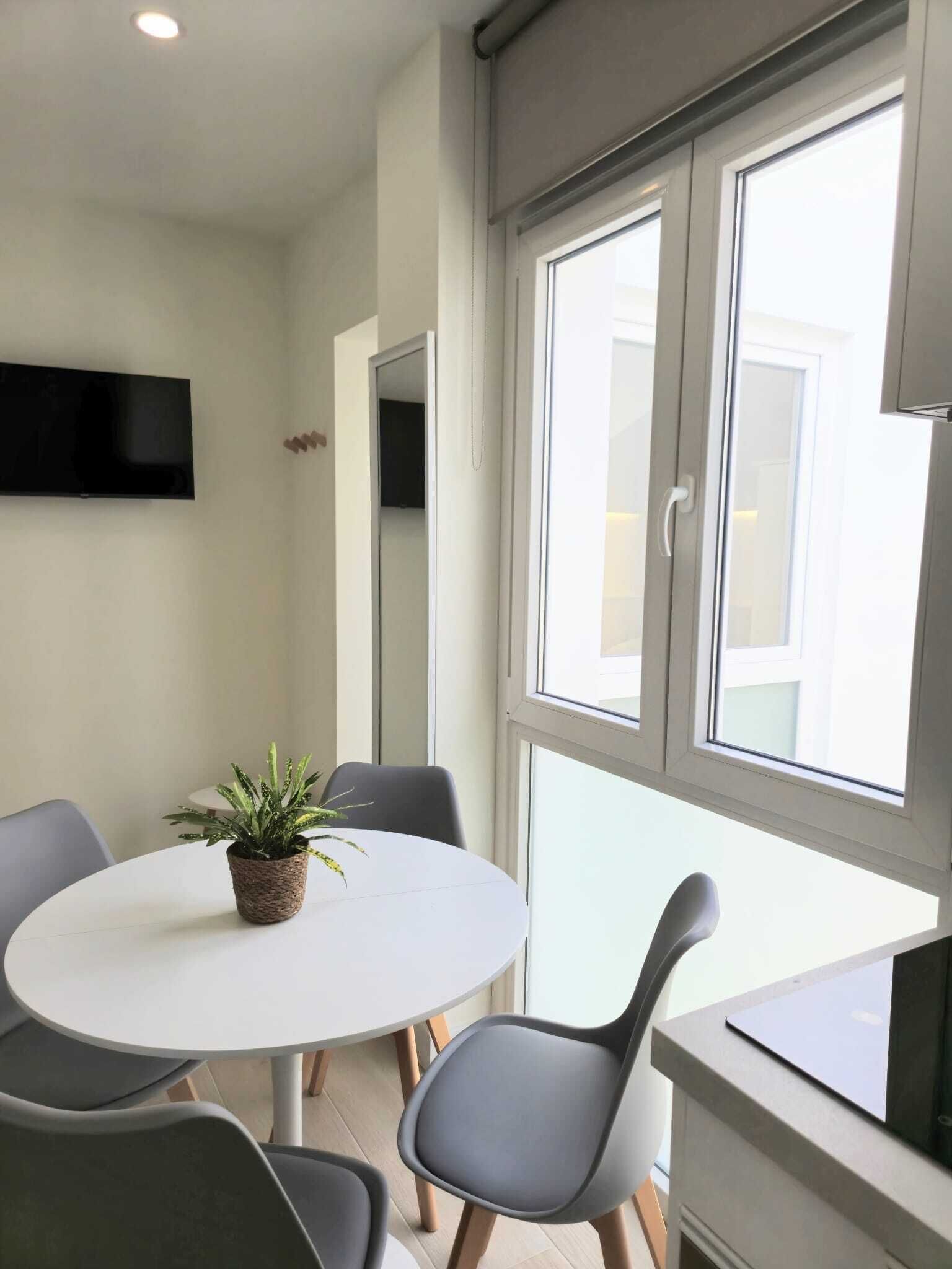 Un comedor moderno con una mesa redonda, sillas grises y una planta en maceta.