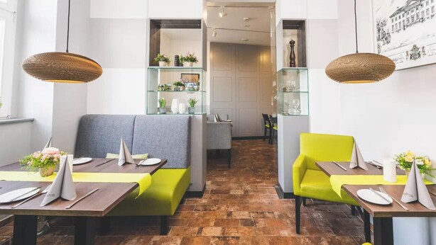Uma sala de jantar moderna com banquetas e cadeiras altas, piso de tijolos e iluminação pendente.
