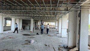 Ένα εργοτάξιο με εμφανείς κολώνες από οπλισμένο σκυρόδεμα και ένα μεταλλικό σκελετό που αποτελεί την οροφή.
