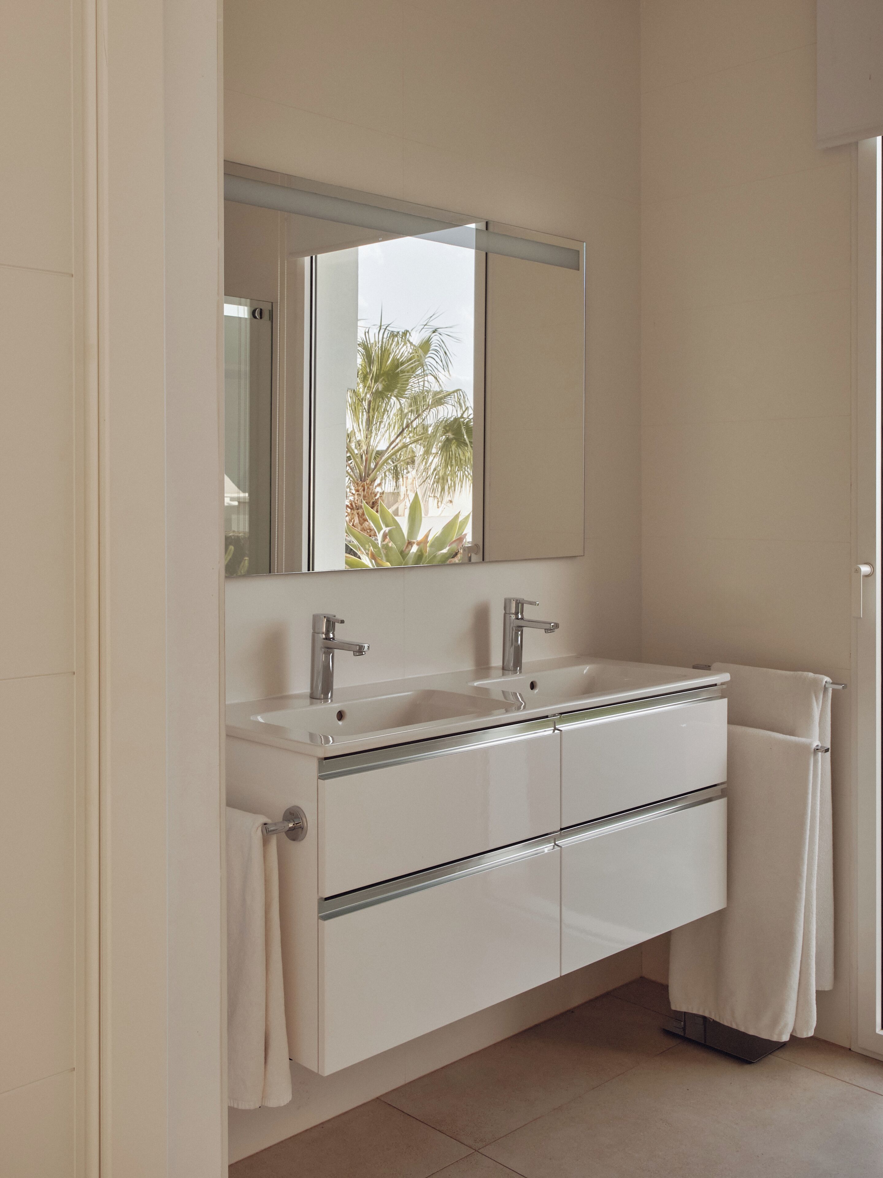 A modern bathroom with a double sink, a large mirror, and a towel rack.