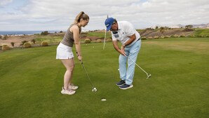 Two people on a golf course with a clear sky and distant mountains. - Villas Element by Villas Alondra (Tías)