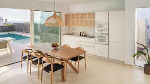 Une cuisine moderne avec des meubles en bois, une table à manger avec des chaises et une vue sur une piscine.