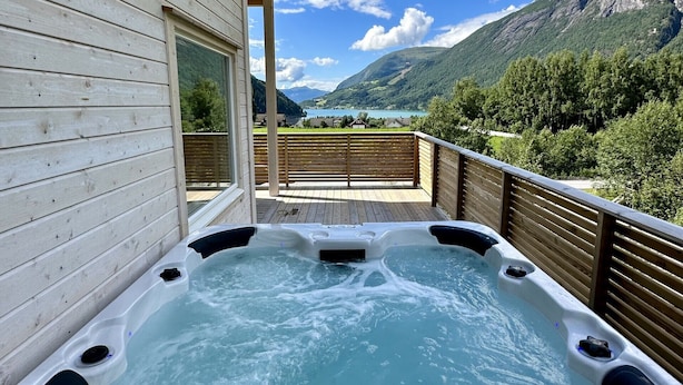 Ein Whirlpool auf einer Holzterrasse mit Blick auf die Berge.