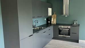 Eine moderne Küche mit grauen Schränken, einer Edelstahlspüle und einem eingebauten Backofen.