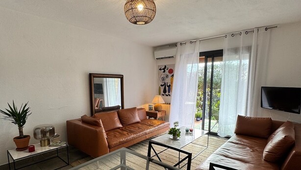 Una sala de estar moderna con una mesa de centro de vidrio, sofás de cuero y una lámpara colgante.