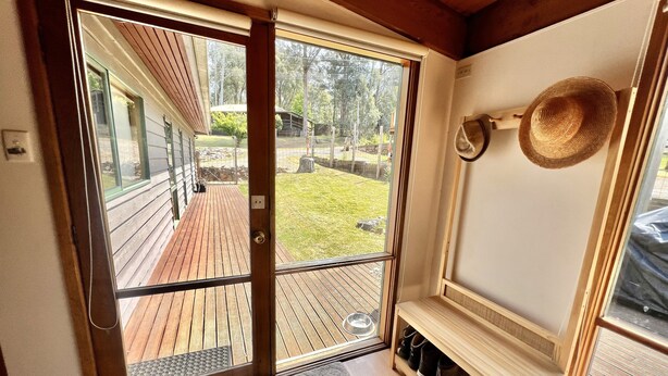 A wooden interior with a sliding glass door leading to an outdoor deck. - Albaski Lodge – Room 2 (Sawmill Settlement)
