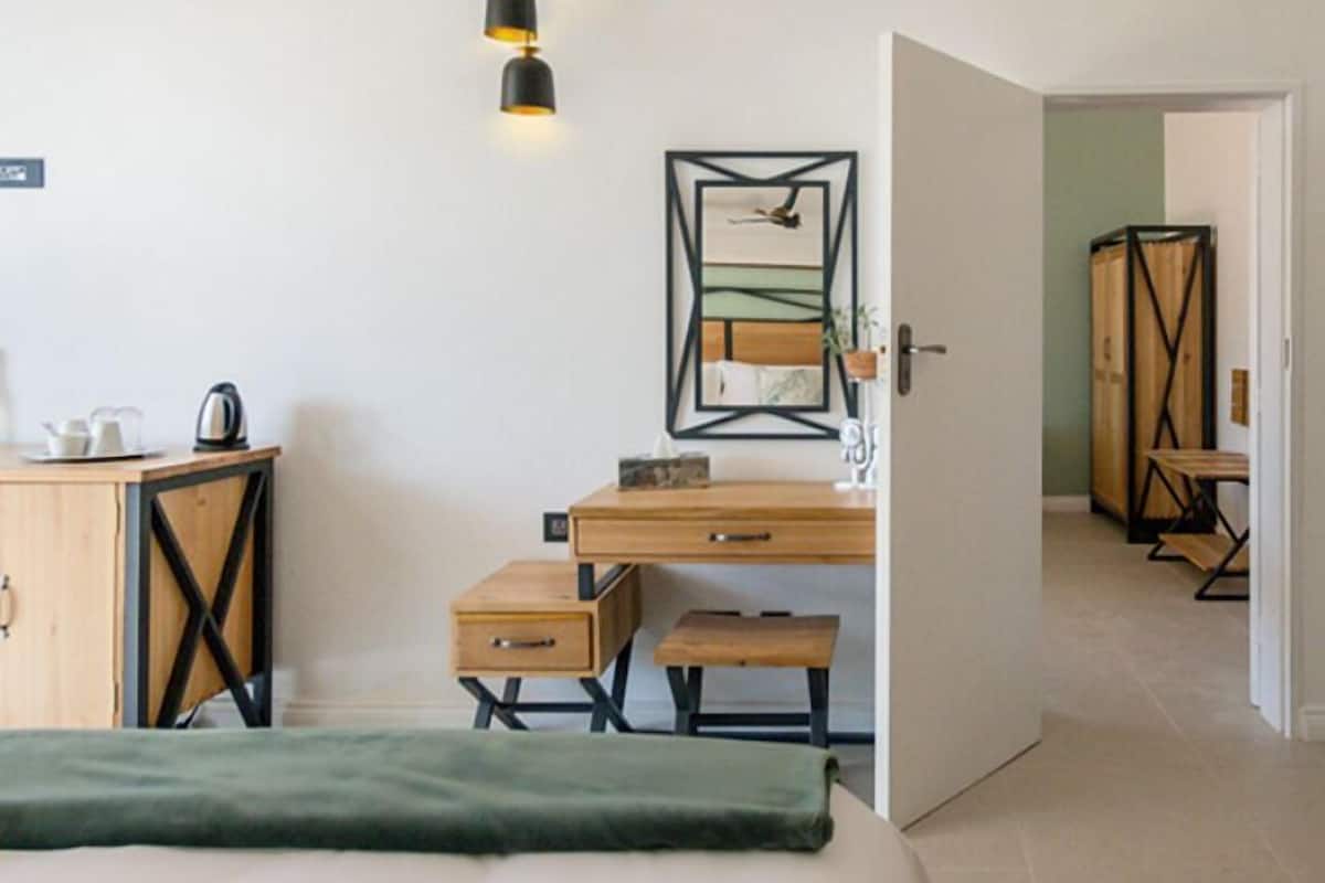 A bedroom with a bed, a desk, a chair, a wardrobe, and a hanging light fixture.