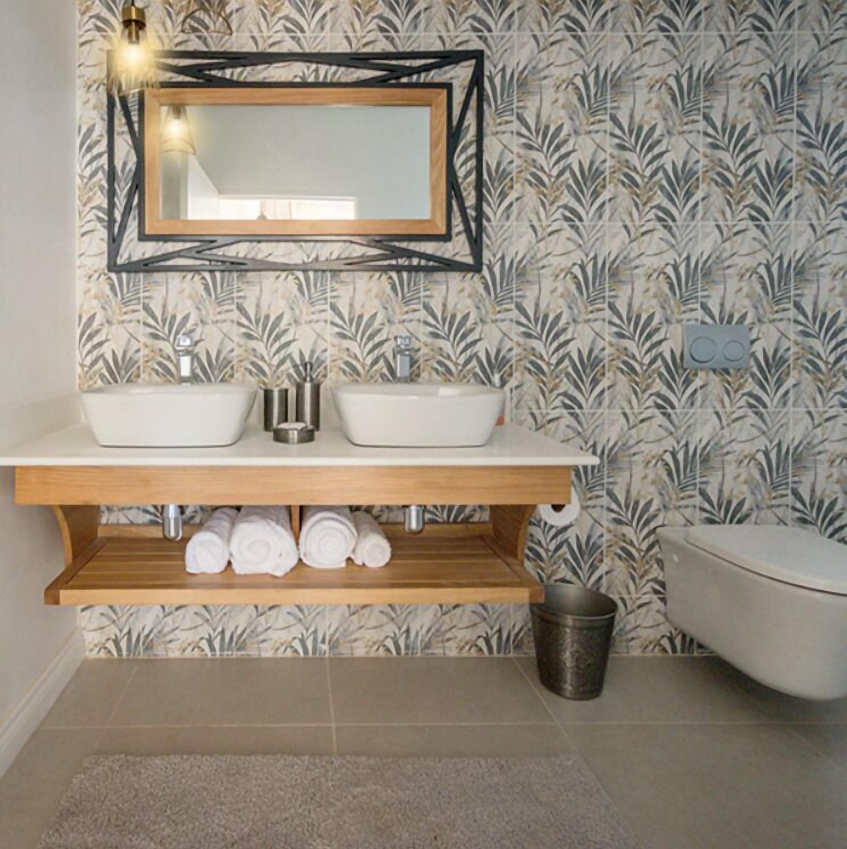 Een badkamer met een houten wastafelmeubel, twee wasbakken, een spiegel en een toilet.