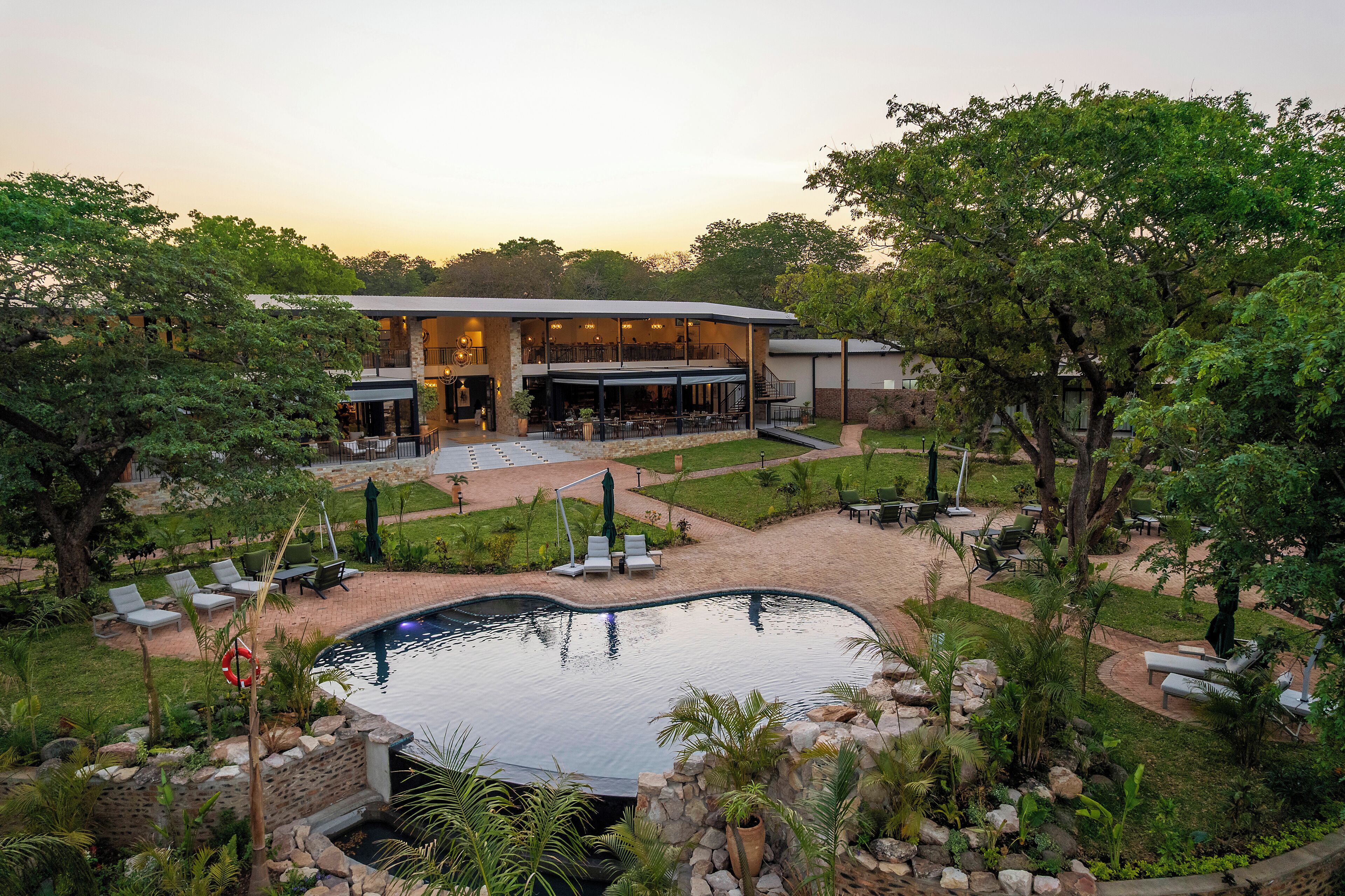 A resort with a swimming pool, outdoor seating, and a building with multiple levels.