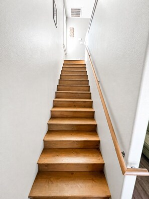 A wooden staircase with white walls and a handrail.