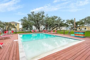 A swimming pool with red lounge chairs and a wooden deck.