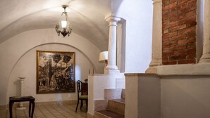 A room with a tiled floor, a painting on the wall, a chair, a table, a staircase with white columns, and a chandelier. - Casa sul Mare by Rentbeat (Vieste)