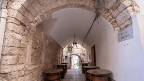 A narrow alley with stone walls and wooden barrels, leading to a doorway. - Casa sul Mare by Rentbeat (Vieste)