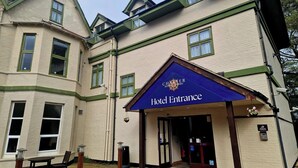 Ingresso di un hotel con insegna che riporta 'Hotel Entrance', in stile architettonico tradizionale e una porta ben visibile.