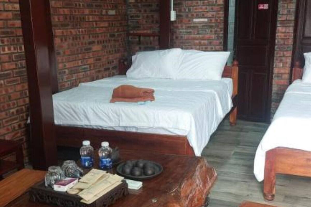 A hotel room with two beds, a wooden table, and a brick wall.