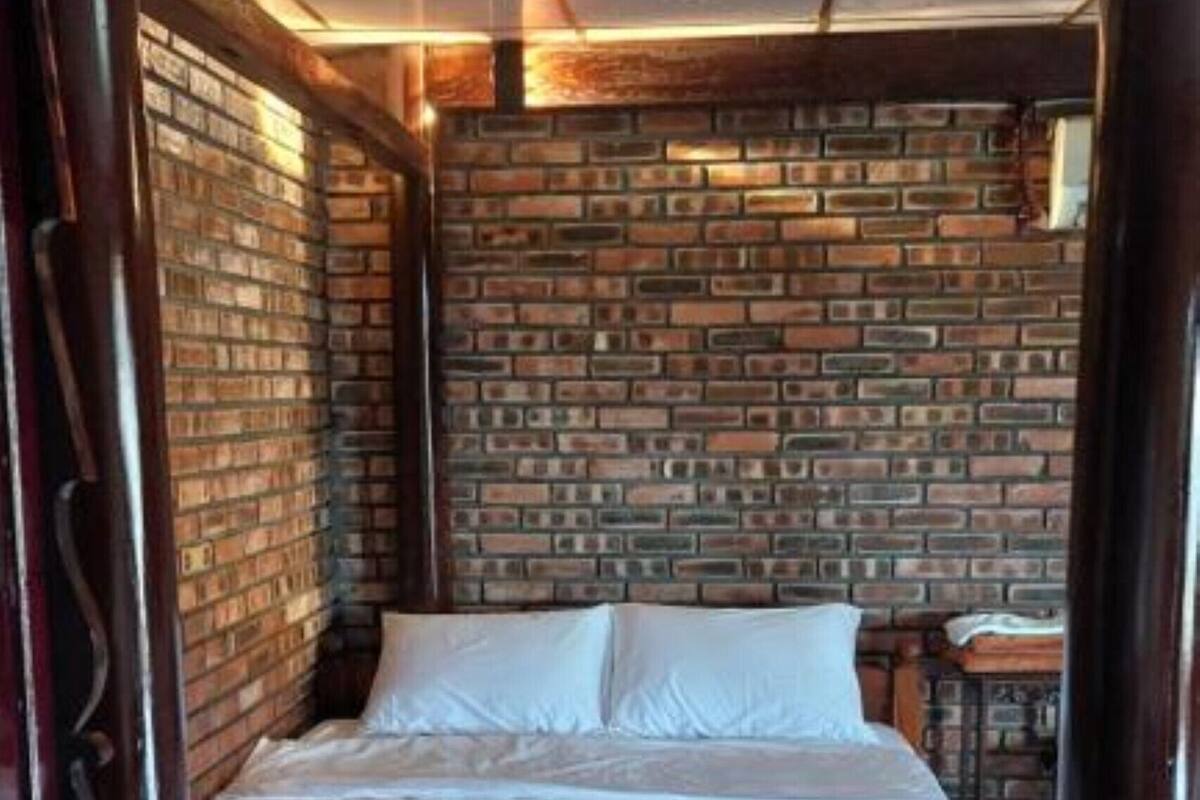 A bed in a room with a brick wall and wooden floor.