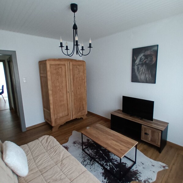 A modern living room with a wooden cabinet, a flat-screen TV, a sofa, and a cowhide rug.