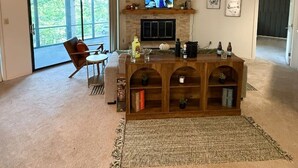 A spacious living room with a fireplace, a television, and a large window.