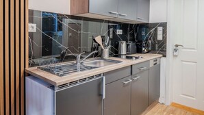 A modern kitchen with a black marble backsplash, stainless steel appliances, and wooden accents. - Cosy tiny flat central Berlin Charlottenburg (Berlin)