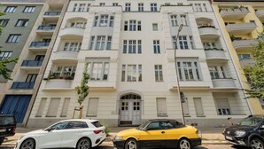 A multi-story residential building with balconies, a central entrance, and a parking area with cars. - Cosy tiny flat central Berlin Charlottenburg (Berlin)